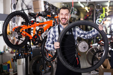 Fototapeta na wymiar man in apron considering composition of wheel for bicycle