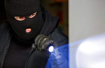 Einbrecher im Haus nachts mit Taschenlampe
