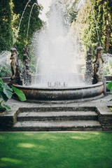 Naklejka premium Beautiful old fountains with sparkling water and statues in sunny botanical garden, on Borromean Islands on Lago Maggiore, Stresa city, Italy. Relaxing on on Lago Maggiore. Summer vacation