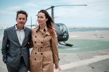 Young business couple near private helicopter