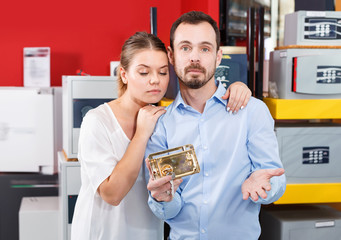 Upset couple choosing door lock for their apartment in store