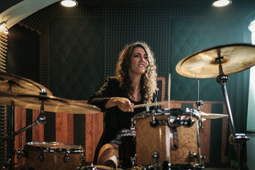 Woman playing drums during music band rehearsal