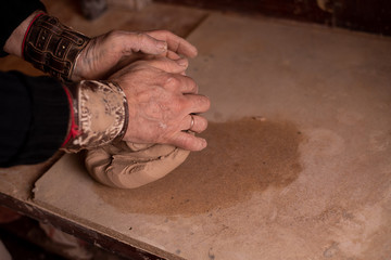 potter's hands work with clay, making it a product