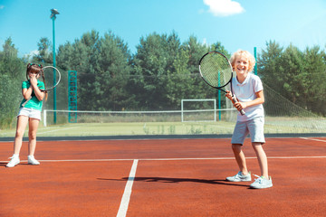 Obraz premium Cheerful brother feeling happy playing tennis with sister
