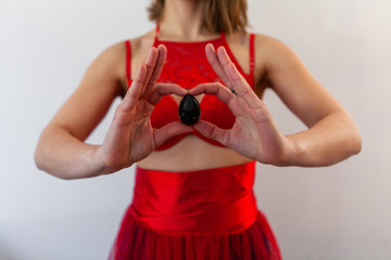 Woman in red lingerie holds jade egg. A spiritual nephrite egg is seen close up, in the hands of a...