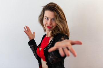 Beautiful girl wears elegant underwear. A stunning young female wears seductive underwear and holds her hand out, inviting towards the camera, with red bra and brown hair.