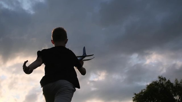 The boy is playing with a toy plane. Sunset. Slow motion.