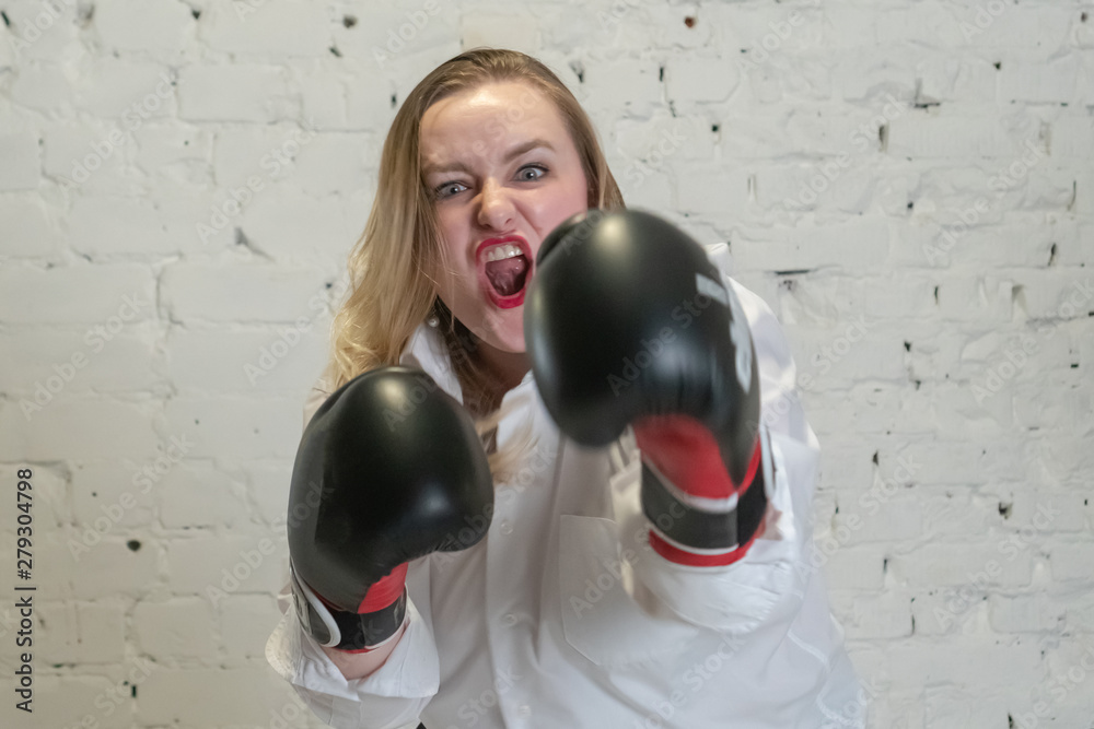 Wall mural the girl in boxing gloves is looking at the camera. emotions anger and aggression. feminism and femi