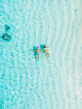 Pregnant woman with husband swim in blue sea. Aerial view