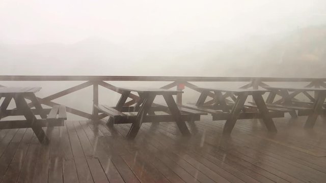 Empty benches in a garden restaurant during extreme cloud-burst