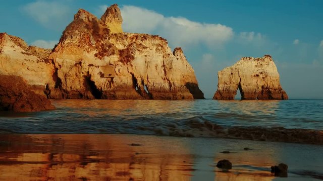 Beautiful sunset slow motion of pristine waters and beautiful rock formations in Tres Irmaos Beach in Alvor, The Algarve, Portugal