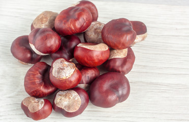 Plenty of chestnuts in a pile on a white wooden table. View from above.