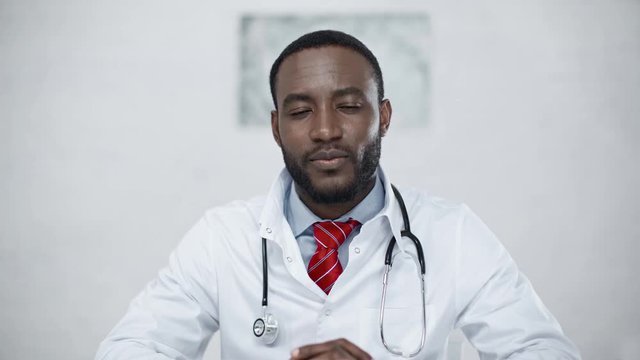 handsome, positive african american doctor smiling while looking at camera