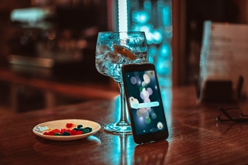smartphone on gin tonic glass and snack in a pub
