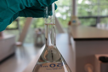 Glass in laboratory hold by gloved hand