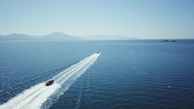 Two speed boats approaching Fenit lighthouse, drone orbiting shot