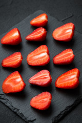 sliced fresh strawberries and mint leaves. dark stone background. 