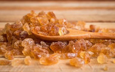 Natural rock sugar in wooden spoon on rustic table