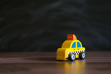 Obraz premium Taxi operator concept. Price of services. Yellow car toy taxi on black background space for text