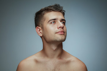Naklejka premium Portrait of shirtless young man isolated on grey studio background. Caucasian healthy male model looking at side and posing. Concept of men's health and beauty, self-care, body and skin care.