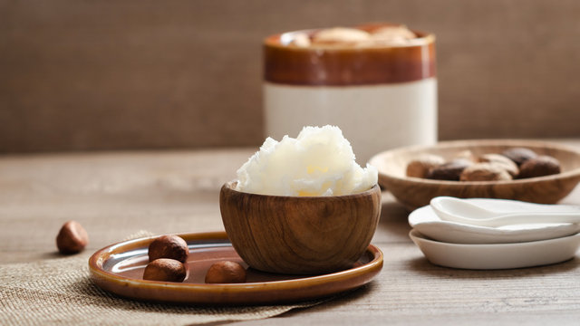 Shea butter in wooden bowl with nuts . Free text space.