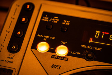 Fototapeta premium Closeup of 'Cue IN/OUT' buttons on a CD Player. Yellow stage lighting.