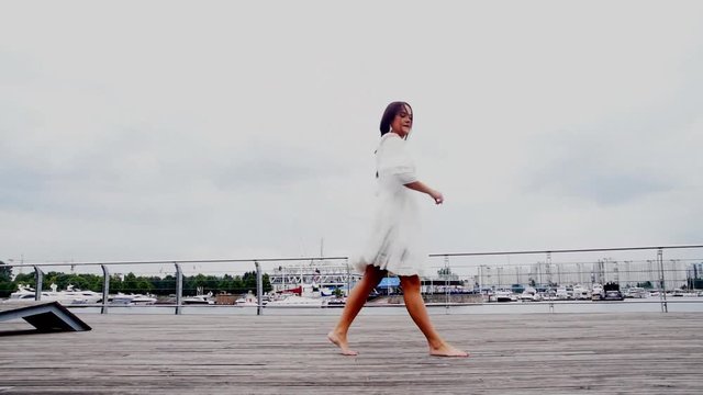 the waterfront girl in a white dress dancing