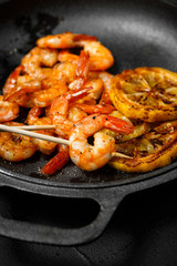 grilled shrimp skewers, lemon, pepper on dark background. barbecue shrimps. shrimp sriracha kebabs