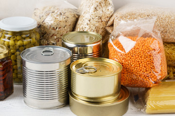 Various canned food and raw cereal grains on a table.