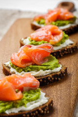 open sandwich with avocado and salmon on wood board
