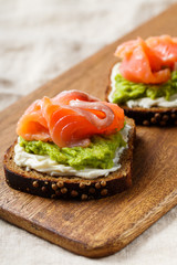 open sandwich with avocado and salmon on wood board