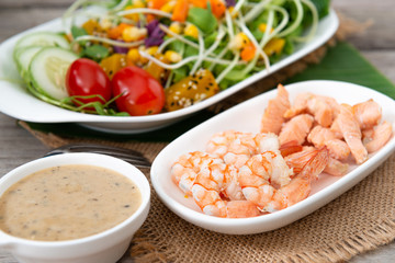 Fresh salad plate with shrimp, salmon, tomato and mixed greens  on wooden background .