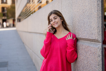 Attractive young student woman talking and chatting on her smart phone outside in an European city