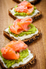 open sandwich with avocado and salmon on wood board
