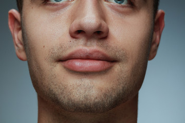 Close-up portrait of young man isolated on grey studio background. Caucasian male model's face and...