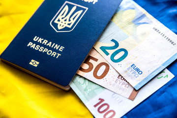 Obraz premium Ukrainian passport on the background of the Ukrainian flag with euro banknotes of different denominations.