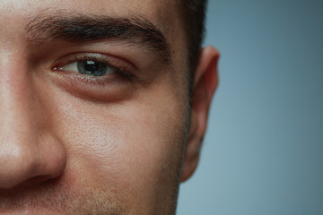 Obraz premium Close-up portrait of young man isolated on grey studio background. Caucasian male model's face and blue eye. Concept of men's health and beauty, self-care, body and skin care, medicine or phycology.