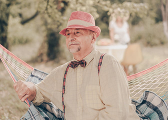 Happy smile elderly senior man portrait. Caucasian old grandfather on hammock in the garden...
