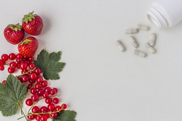 Vitamins supplements as a capsule with fresh berries from the medicine jar on white background.