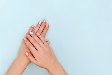 Woman's hands with pastel manicure on blue background. Copy space.