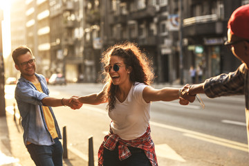 Group of friends hangout at the city street.They hold hands and laughing.