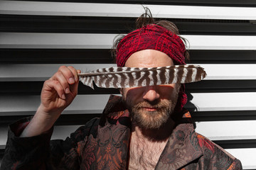 Sacred man meets urban environment. A closeup view of a poetic man wearing a red bandanna by modern...