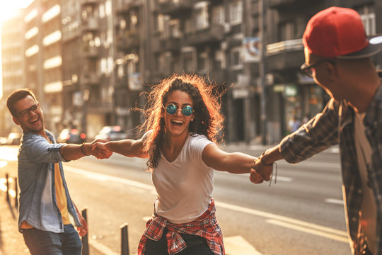 Group of friends hangout at the city street.They hold hands and laughing.