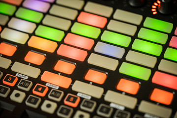 Electronic music production in a home studio. Closeup of coloured LED pads on a midi controller.