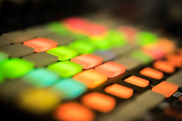 Electronic music production in a home studio. Closeup of coloured LED pads on a midi controller.