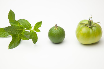 Fototapeta na wymiar Fruta verde, naranja verde, menta y tomate verde, tres tonalidades de verde distintos. Color verde