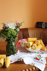 a bouquet of flowers and a plate of corn on the table 