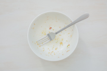 Rice scraps with vegetables in a white bowl on a white table