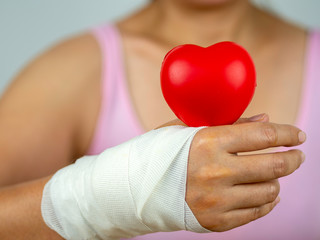 Red heart placed on hand injury and bandage. Happiness even when injury