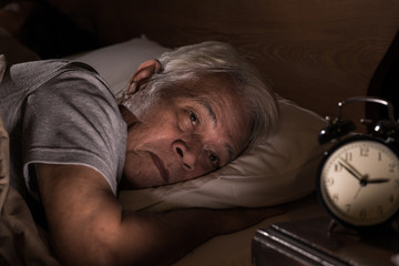 Depressed senior man lying in bed cannot sleep from insomnia